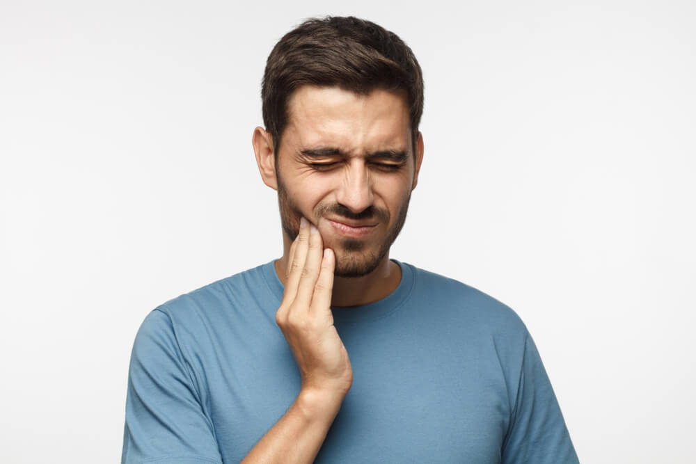 young male suffering from bad toothache